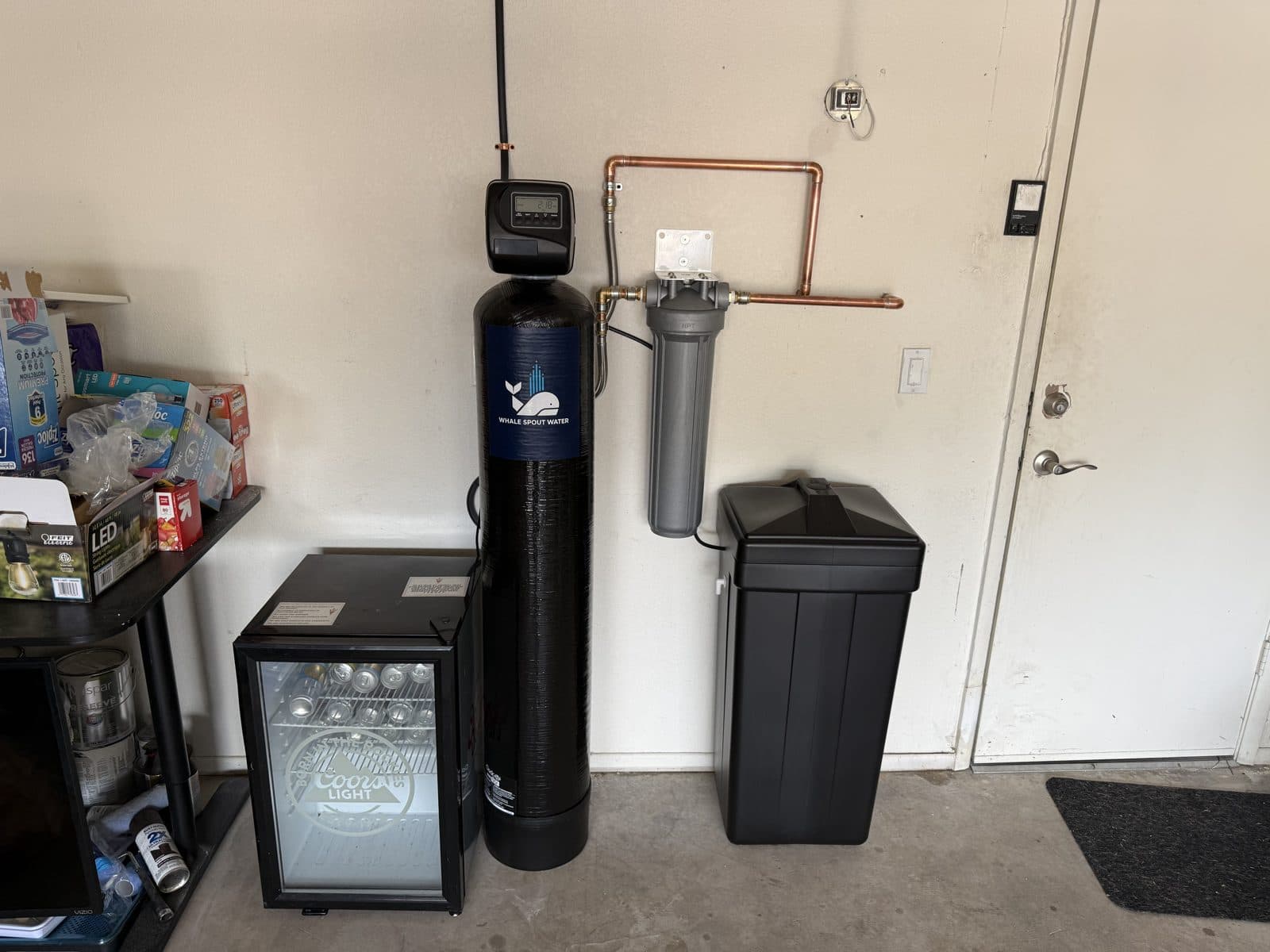 Salt-based water softener with a whole-home filter housing and brine tank installed in a garage